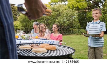 Little boy waiting for barbecue cooked by father standing and holding his plate
