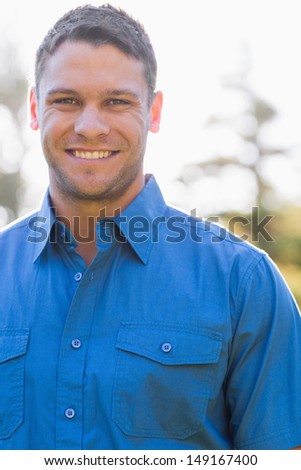 Attractive man with short hair and a blue shirt looks at the camera