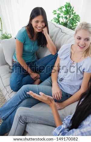 Friends having a chat and laughing at home on the couch