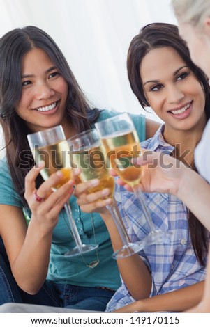 Cheerful friends enjoying white wine together at home on the couch
