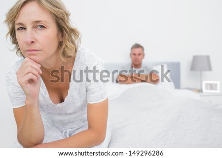 Angry woman looking at camera after fight with husband in bedroom at home