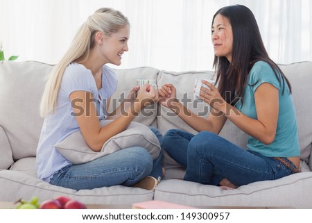 Friends drinking coffee and talking at home on the couch