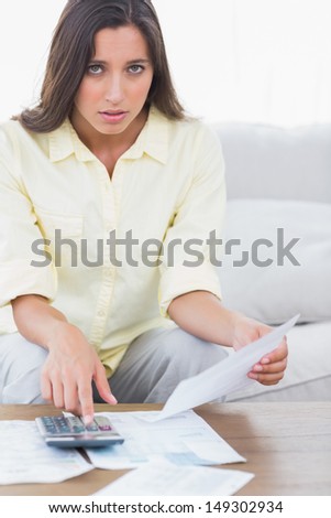 Fearful woman doing her accounts sat on a couch