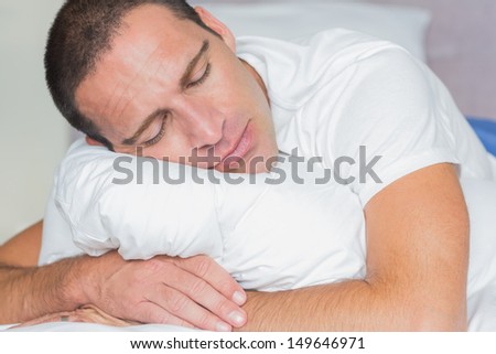 Sleeping man hugging his pillow at home in the bedroom