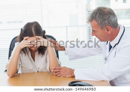 Serious doctor comforting his patient after telling her diagnosis in bright surgery