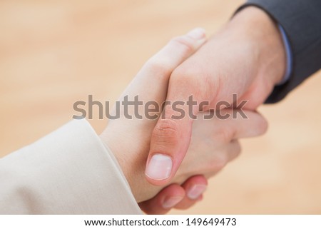 Close up on new partners shaking hands in bright office