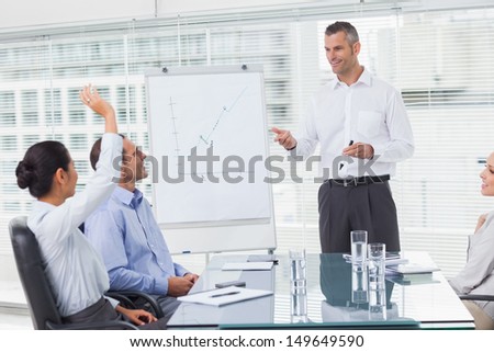 Businesswoman asking question during her colleagues presentation in bright office