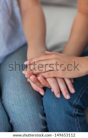 Close friends holding hands at home on the couch