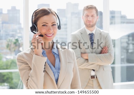 Happy call center agent with colleague standing behind her in office
