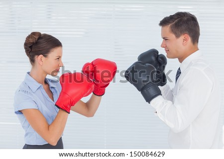 Colleagues in competition having a boxing match in bright office