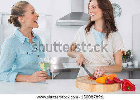 Brunette cooking while talking to her friend in her kitchen