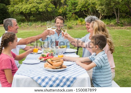 Multi generation family toasting each other at dinner outside at picnic table