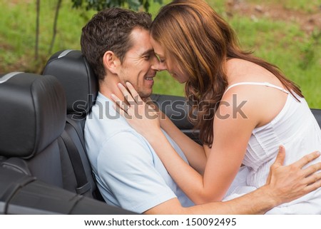 Young couple feeling romantic in back seat of convertible in countryside