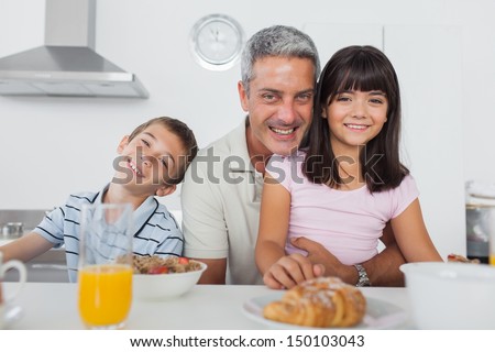 Siblings eating breakfast in kitchen together with dad at home