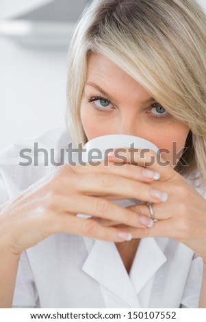 Happy woman sipping coffee in the morning looking at camera