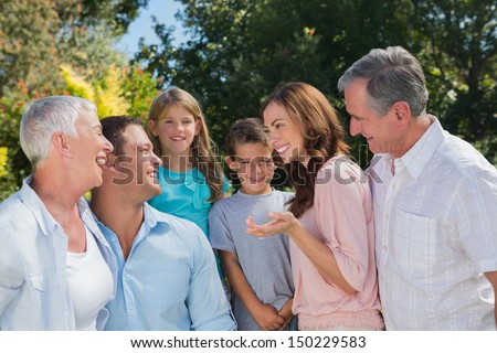 Smiling family and grandparents talking in the park together