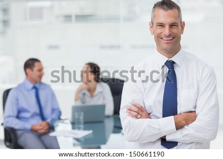 Smiling businessman posing crossing arms in bright office