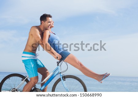 Man giving girlfriend a lift on his crossbar of bike on the beach