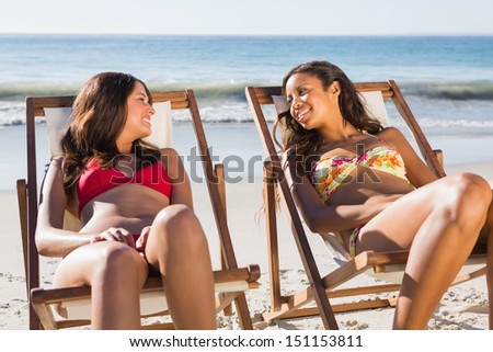 Cheerful friends on the beach relaxing on their deck chairs