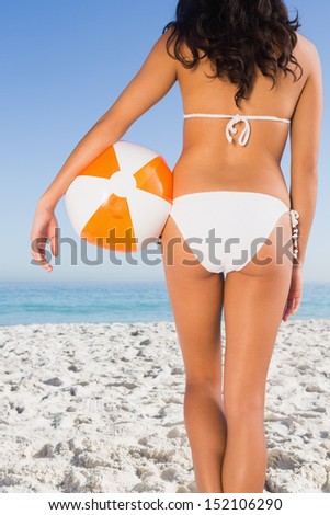 Back of woman's perfect body holding beach ball on the beach