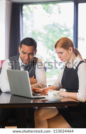 Smiling business team working together in a cafe with laptop