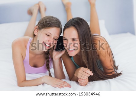 Girls on the phone at girls night in at home lying on bed