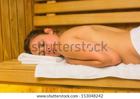 Calm brunette lying down in a sauna and relaxing on white towel