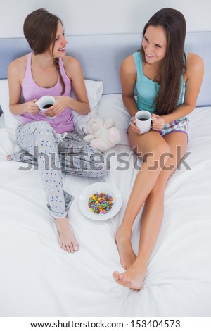 Friends sitting with coffee in bed and talking