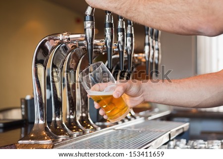 Mans Hand Pouring Pint Of Beer Behind The Bar