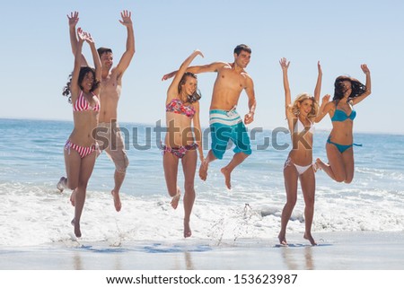 Happy friends jumping on the beach against ocean on holidays