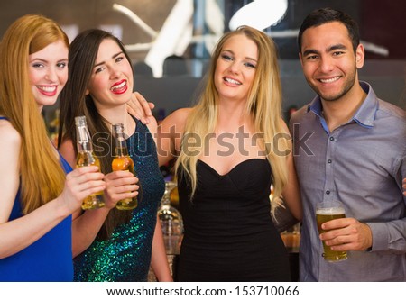 Portrait of smiling friends drinking beers at the nightclub