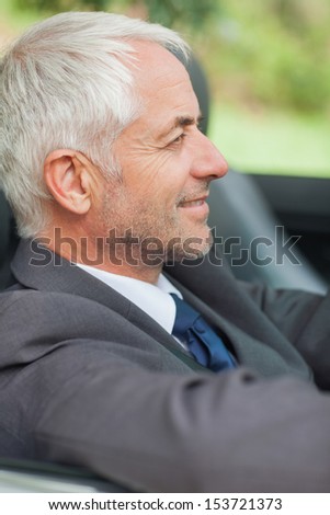 Relaxed businessman driving cabriolet on sunny day