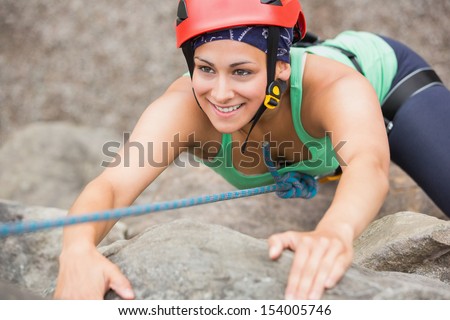 Happy girl climbing rock face wearing red helmet Happy girl climbing rock face wearing red helmet