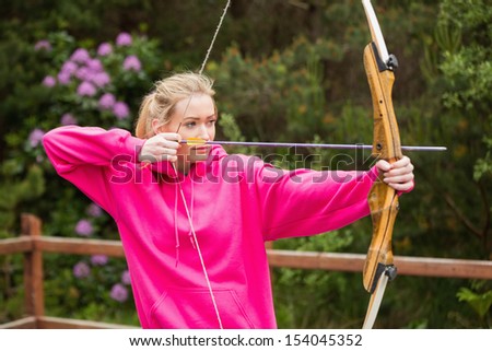 Concentrating blonde practicing archery at the range