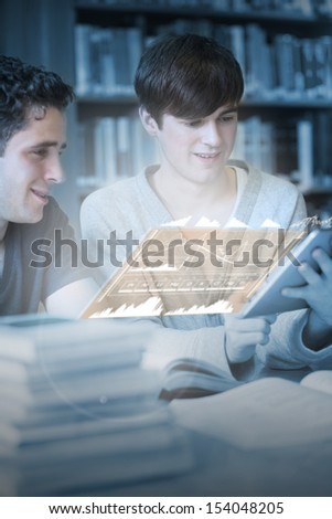 Happy students working together on their digital tablet in university library
