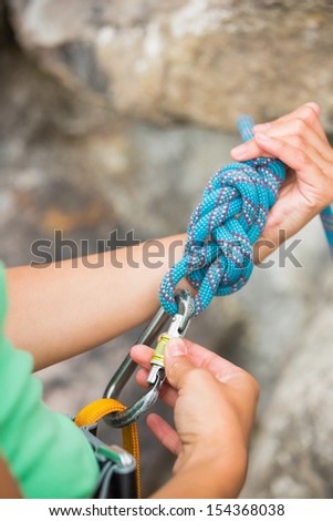 Female rock climber adjusting her harness by the rock face