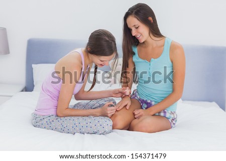 Girl painting her friends nails on bed at girls night