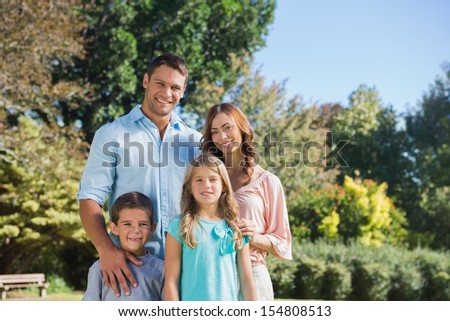 Cheerful family standing in the countryside smiling at camera