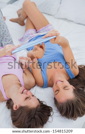 Girls lying in bed with tablet and pointing on it