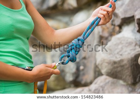 Female rock climber adjusting harness by the rock face