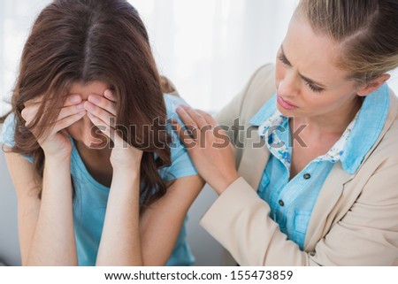Upset woman being comforted by her understanding therapist and sitting on the couch