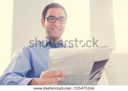 Happy man with glasses looking at camera and holding a newspaper