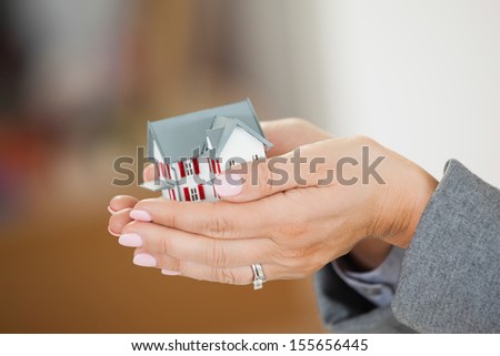 Woman holding a tiny house in her hands with a blurred background