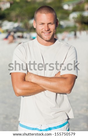 Handsome happy man in swimsuit and tshirt posing on the beach