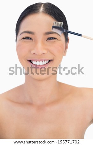 Cheerful pretty natural model using eyebrow brush on white background