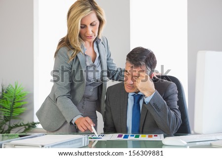 Frowning blonde businesswoman explaining figures to an attentive mature businessman at
