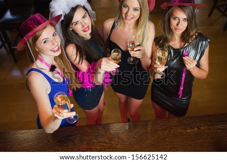 Happy gorgeous women holding flutes of champagne having hen party in a classy bar