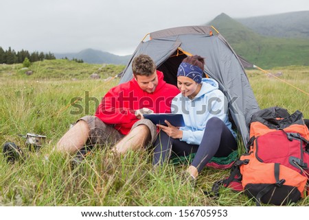 Couple on camping trip using a digital tablet outside their tent