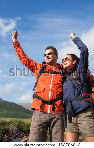 Couple on a hike cheering and smiling in the countryside
