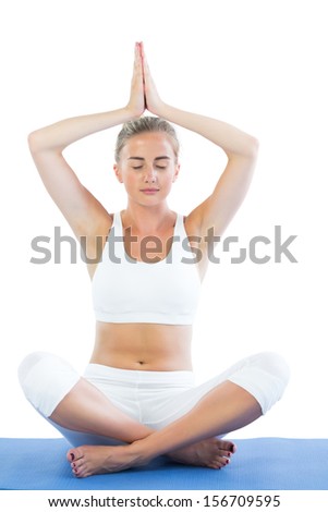 Toned calm blonde sitting in lotus pose meditating on white background